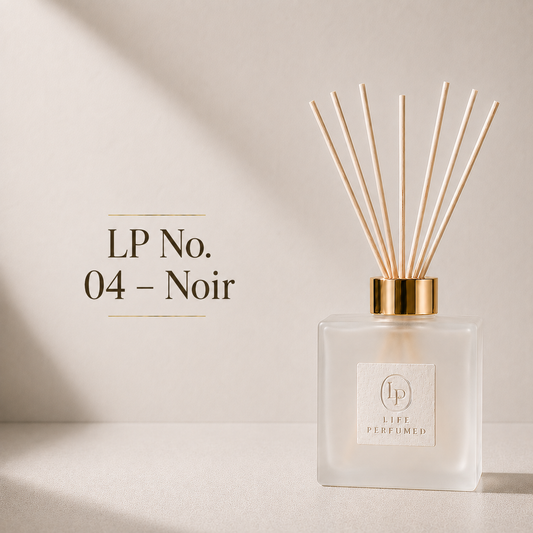 A Life Perfumed reed diffuser bottle with a frosted glass body, gold collar, and natural wood reeds, shown on a warm beige background with the text 'LP No. 04 - Noir'. An irresistible blend of warm spices, rich amber and smooth tobacco creates a fragrance full of confidence and character. Noir is bold, elegant and designed for those who appreciate timeless luxury.