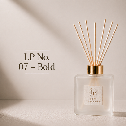 A reed diffuser bottle with a frosted glass body, gold collar, and natural reeds, shown on a warm beige surface with text reading 'LP No. 07 - Bold' on the left. A bold blend of fresh bergamot, aromatic lavender and warm amber creates a powerful fragrance that feels confident, rugged and effortlessly masculine. Fresh, intense and sophisticated, Bold brings an unmistakable sense of adventure to every drive.
